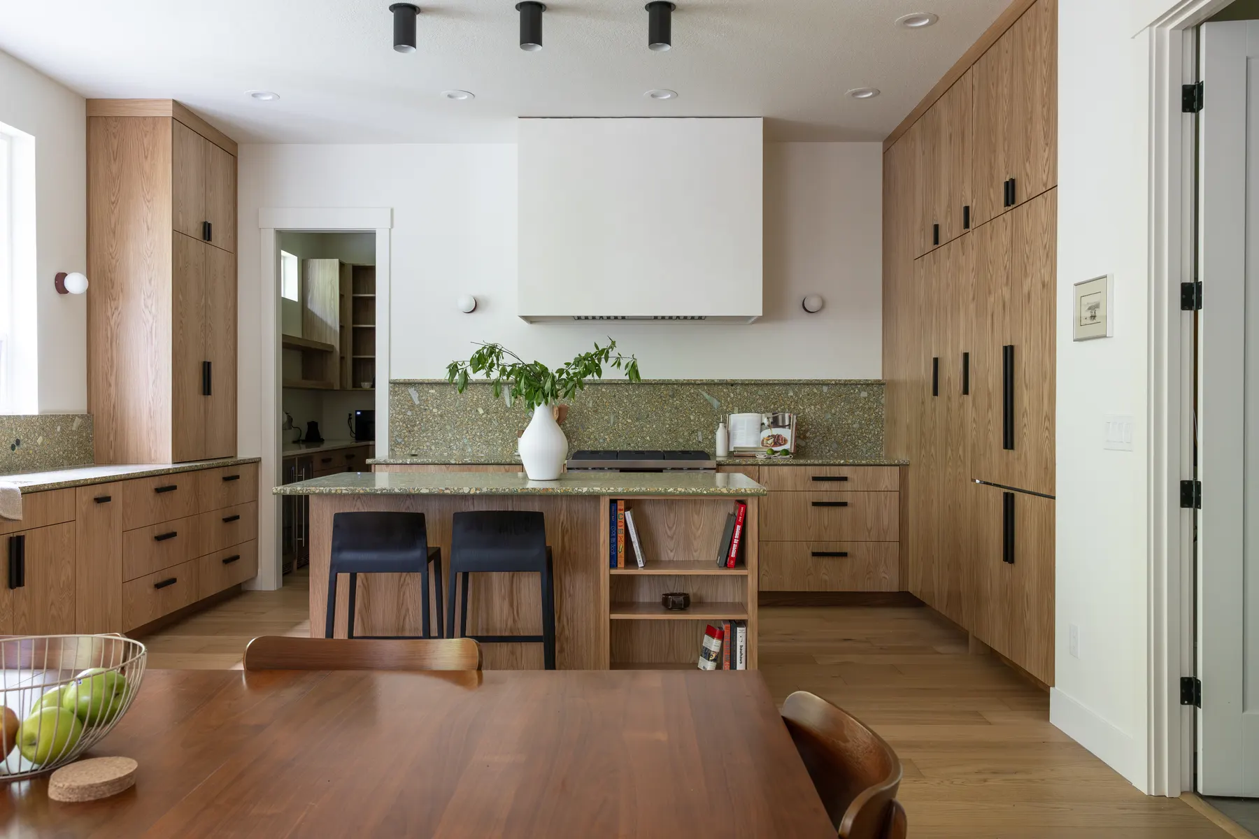 Kitchen after remodel with rift oak cabinetry, green stone backsplash and plaster hood