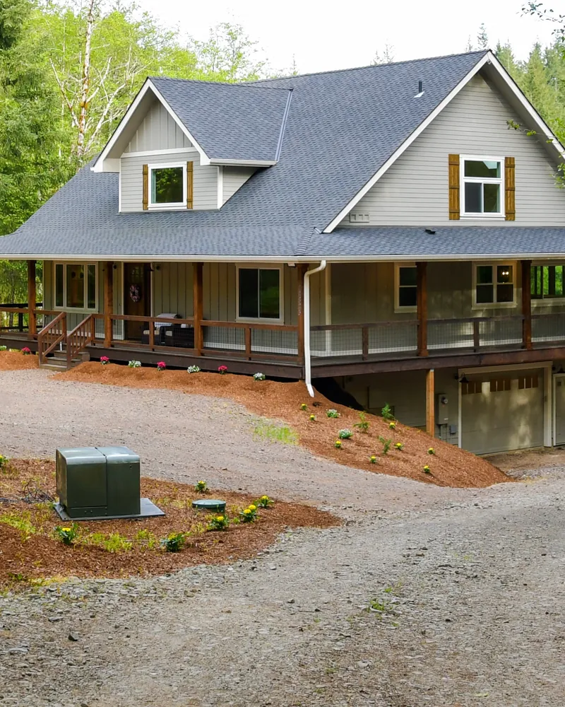 Farmhouse exterior after a remodel, with new siding, trim and a wraparound covered porch