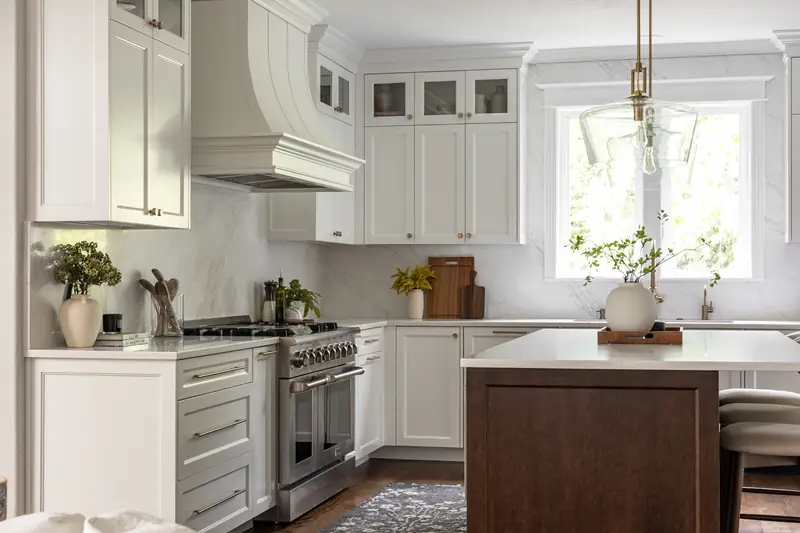 White kitchen with a curved painted range hood, stainless range and stained wood island