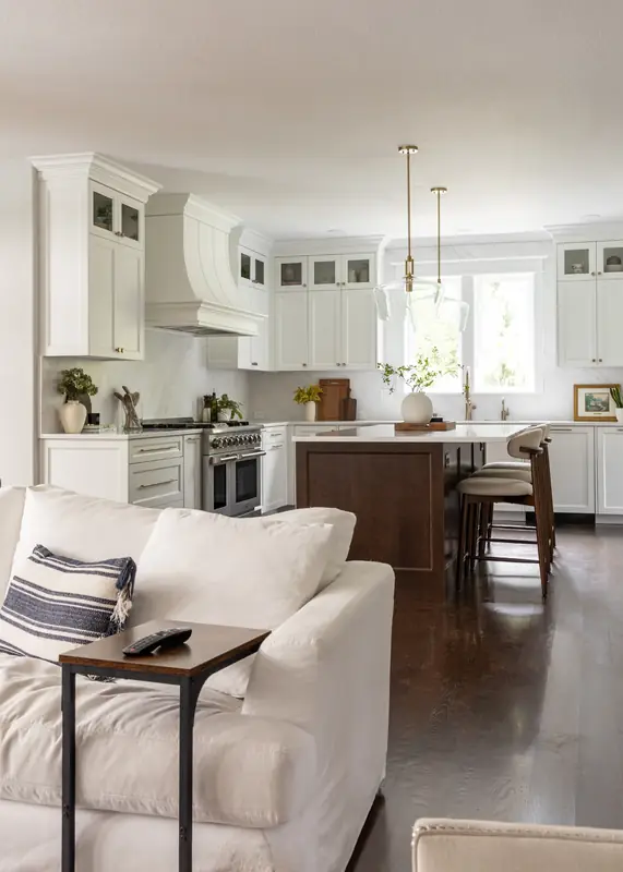 Open-concept view from the living room sofa into the white kitchen and stained island