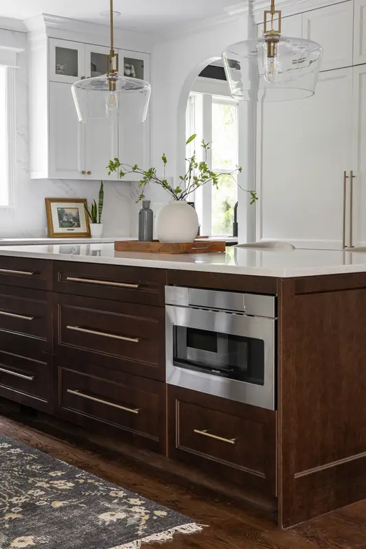 Close-up of the stained wood island's deep drawers, brass pulls and microwave drawer