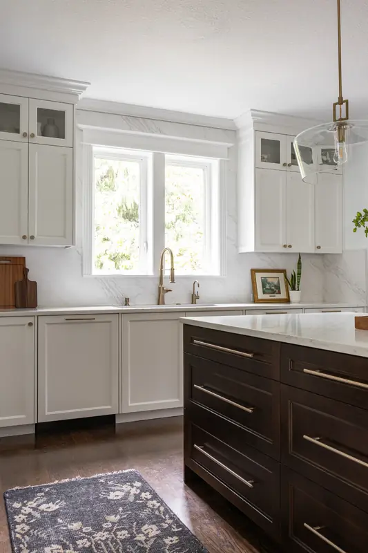 Sink beneath the kitchen window with a brass faucet, beside the stained wood island