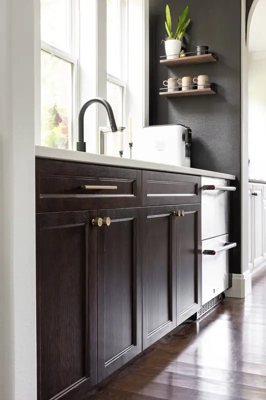 Butler's pantry with dark stained cabinets, a matte black faucet and floating wood shelves