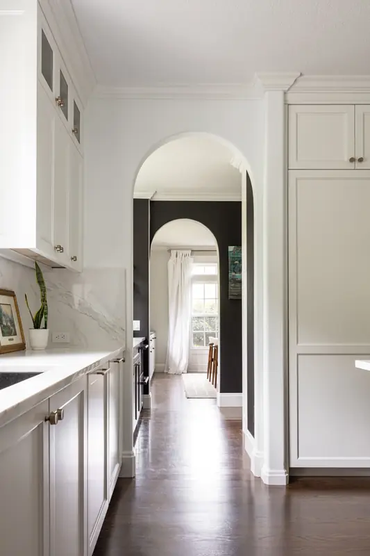 Hallway view through a series of arched doorways, framed by white cabinetry