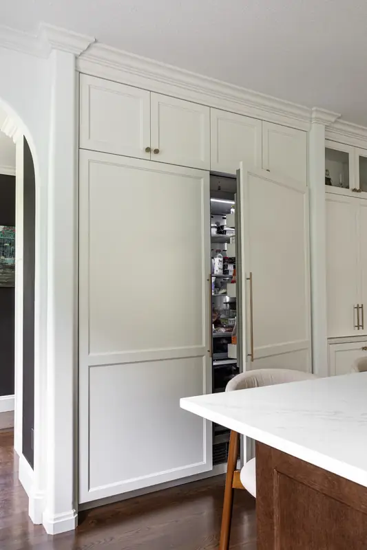 Paneled refrigerator with its door open, flush with the tall white cabinet wall