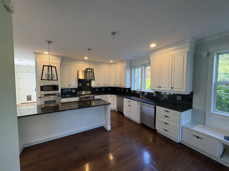 Before the remodel: the original white kitchen with black granite counters, a long island and a small stainless hood over the range