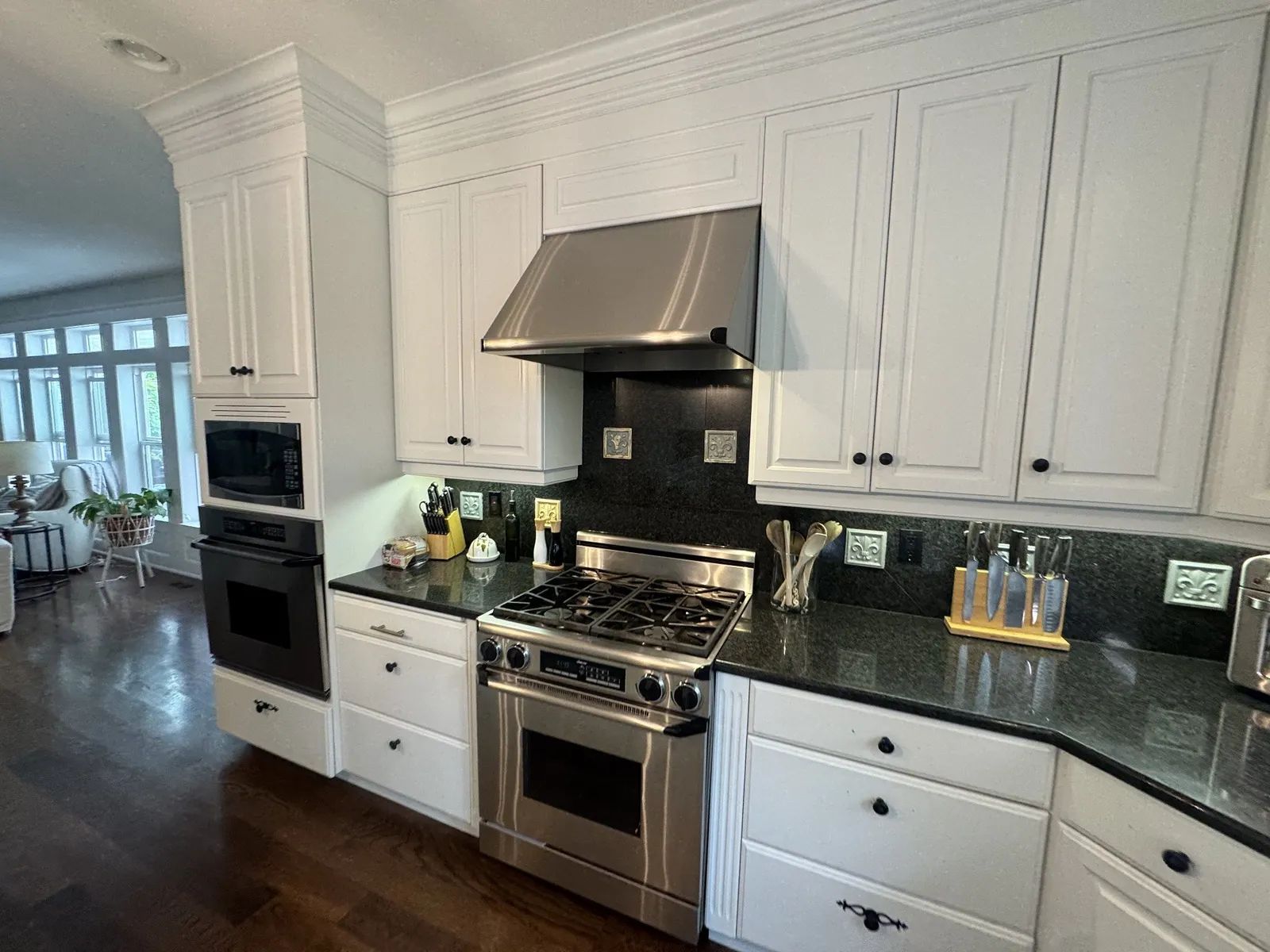 The original range before remodeling, under a narrow stainless hood with a dark tile backsplash and black granite