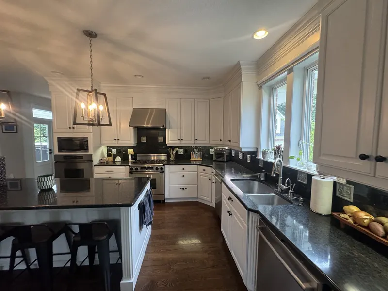 Before the remodel: the original sink run along the window wall, with black granite counters and a lantern pendant over the island