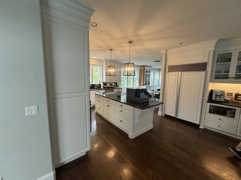 Before the remodel: the original built-in refrigerator and glass-front hutch seen from the hallway, with the island beyond