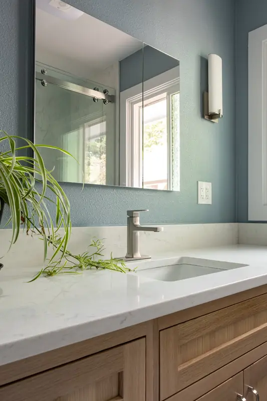 Undermount sink and brushed nickel faucet on a white quartz counter over the wood vanity