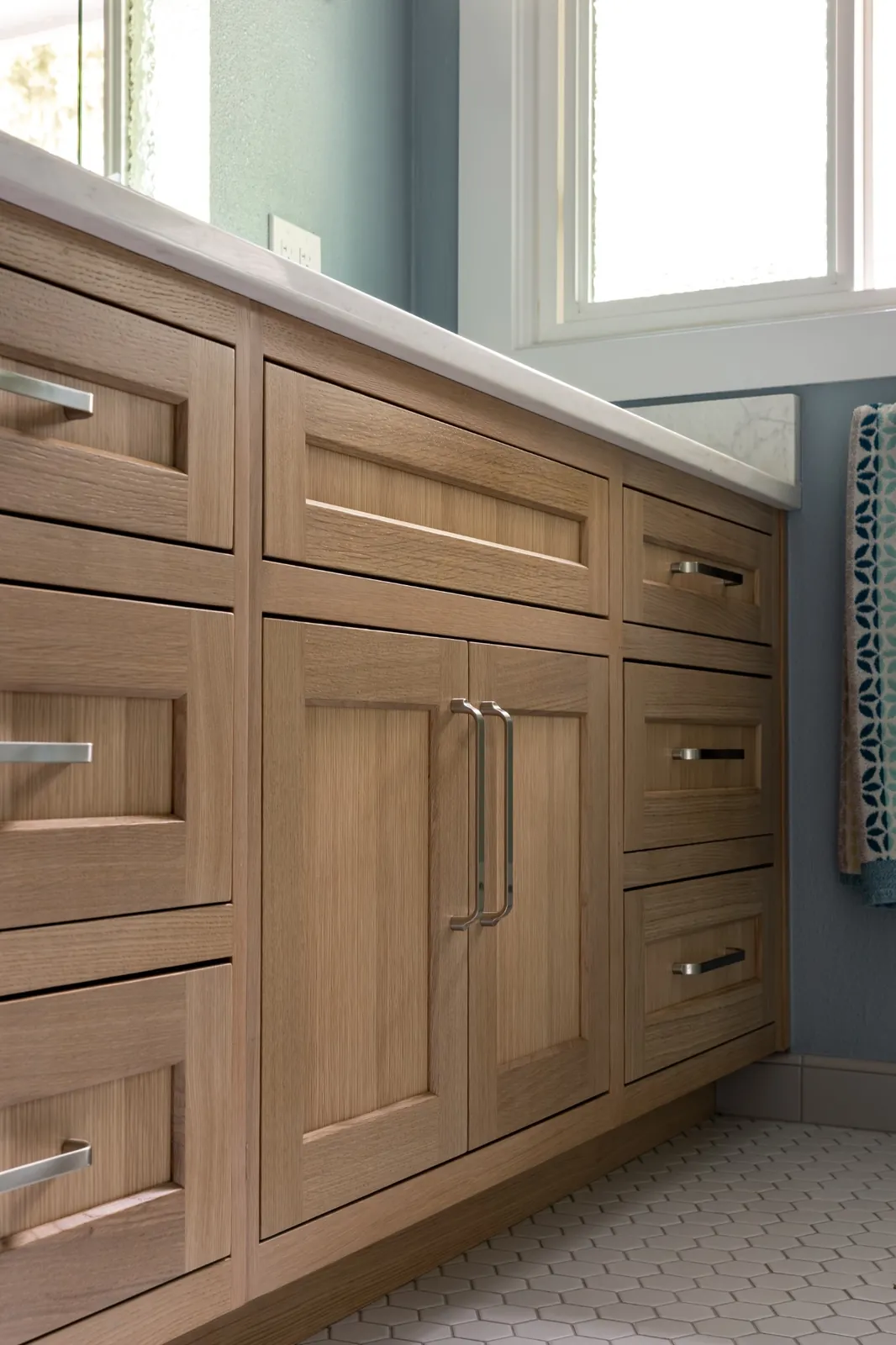 After remodeling: custom stained wood vanity cabinetry with shaker drawers and brushed metal pulls built into the reclaimed wall
