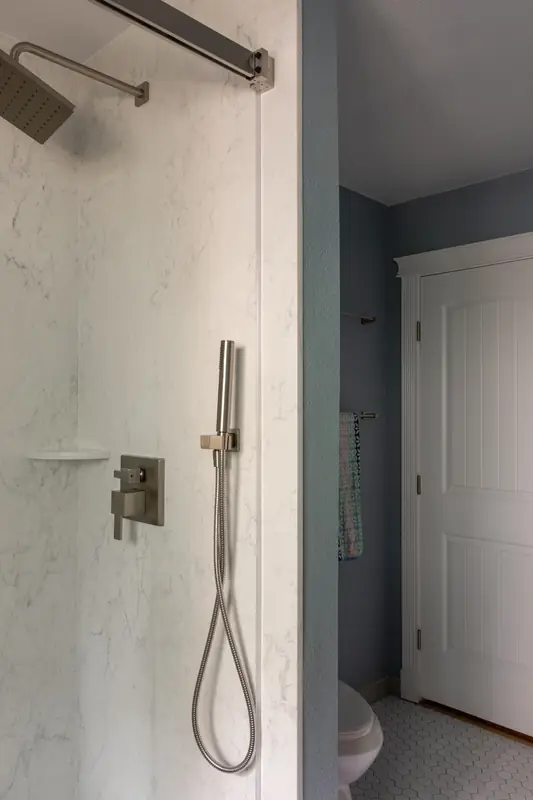 Shower fixtures with a view out the glass to the white door
