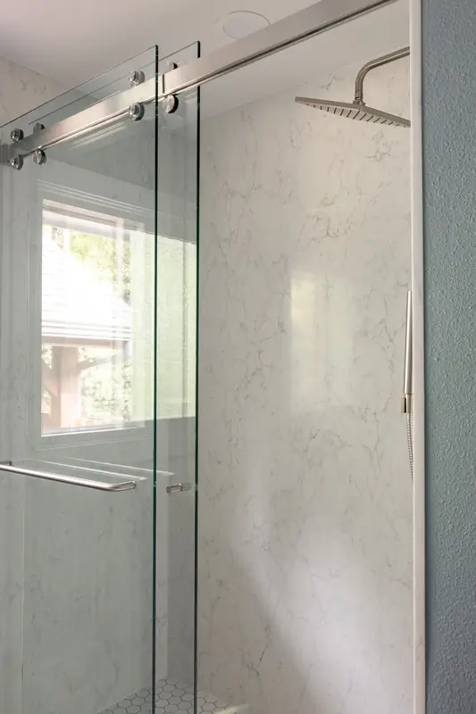 Sliding glass shower doors with a rain head and marble-look walls