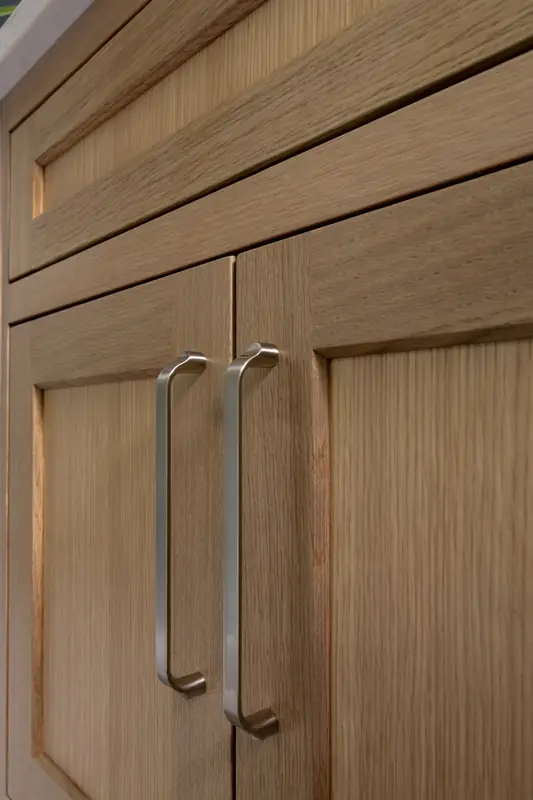 Vanity doors in warm wood with long brushed metal handles