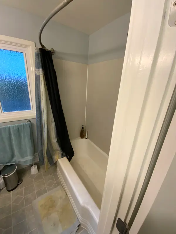 Before the remodel: the small alcove tub with an acrylic surround and curved curtain rod