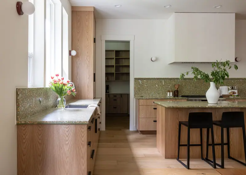 The sink counter in the foreground and the walk-in pantry entry beyond, with oak shelving visible inside the pantry