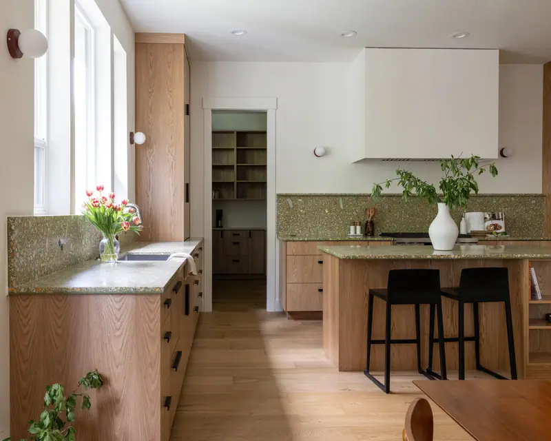 The pantry doorway framed by white oak cabinetry, with the island and plaster hood at the right