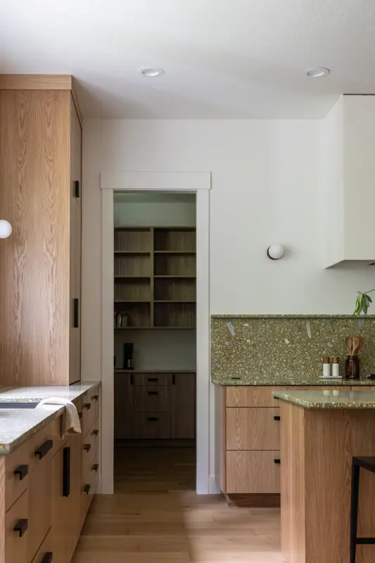 The pantry doorway with its oak shelving, seen between the sink counter and the island