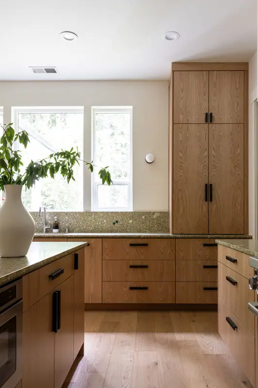 The sink counter with a built-in oven below and the walk-in pantry beyond, on wide-plank oak floors