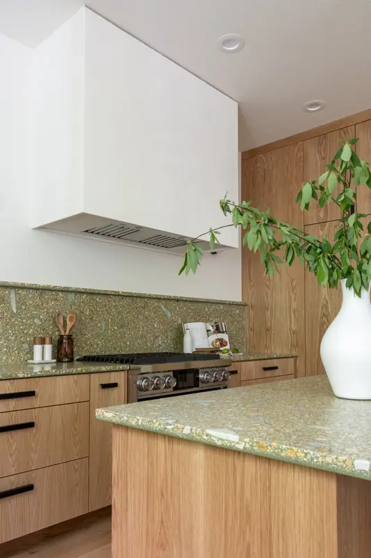 The plaster hood and quartz backsplash above the range, with the island and its vase in the foreground