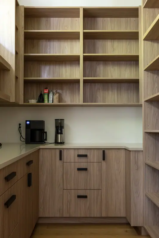 Inside the rebuilt walk-in pantry: custom white oak open shelving above a counter used as a coffee station, with oak base cabinets below