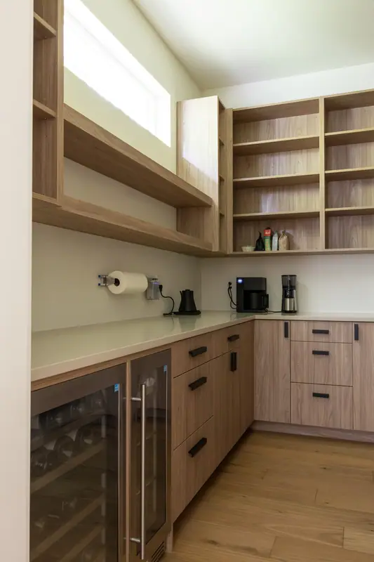 The pantry counter under its clerestory window, with the glass-front wine refrigerator built in below and oak shelving above