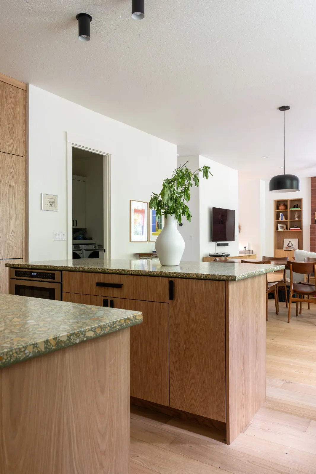 The finished oak island with its terrazzo-look quartz top, looking through the same opening to the living room beyond