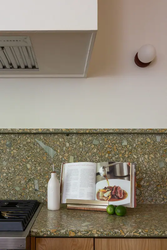 The plaster hood and quartz backsplash above the cooktop, with a cookbook and limes on the counter
