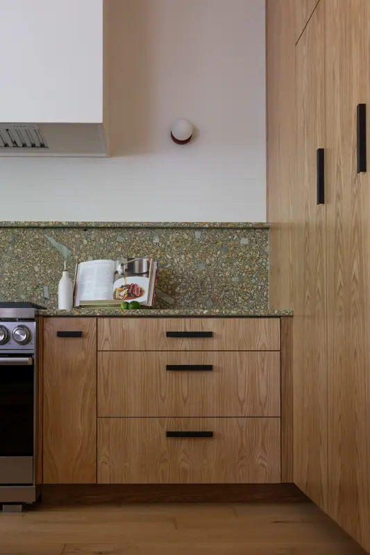The plaster hood and range at the left, with an oak drawer bank and the tall cabinet run to the right
