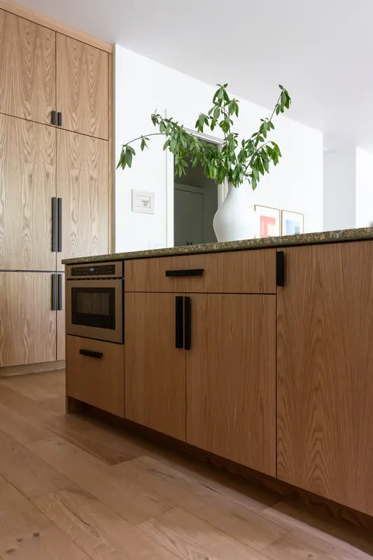 White oak cabinetry with a built-in microwave, looking through to the hall on wide-plank oak floors