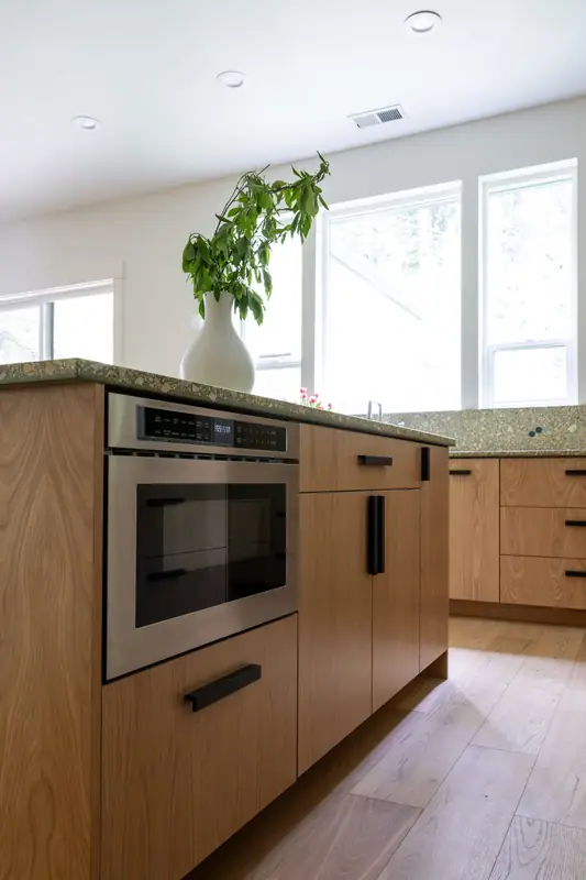 A built-in microwave set into the end of the white oak island, with the window wall behind