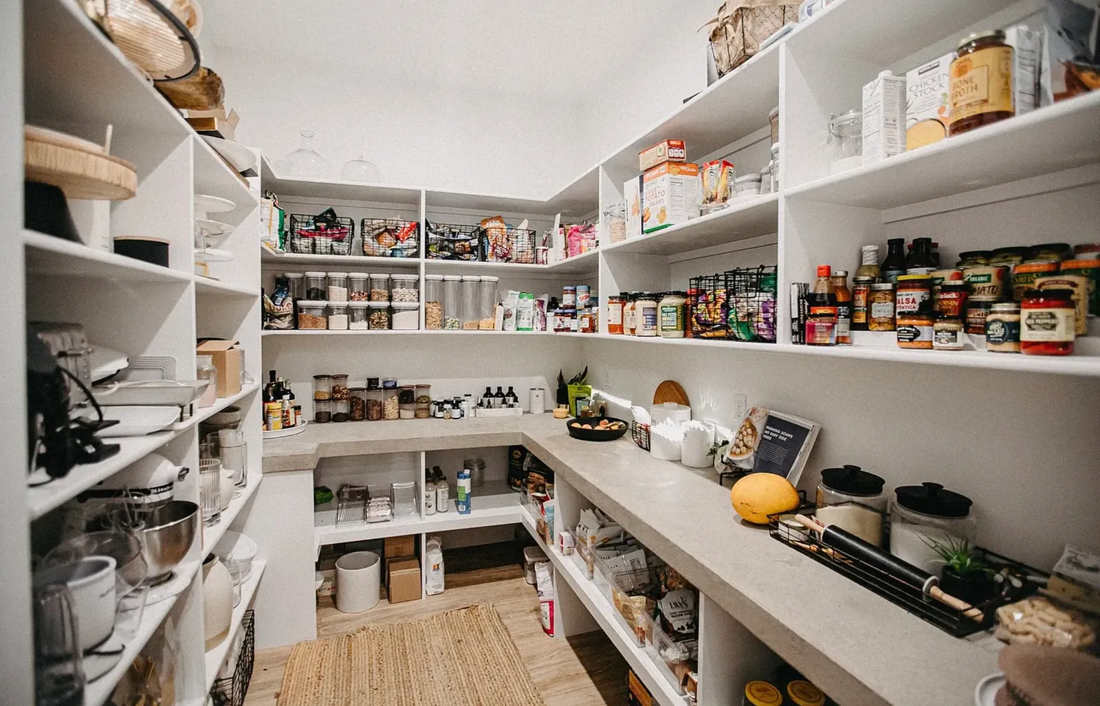 The original walk-in pantry before remodeling, fitted out with plain white open shelving over a white counter