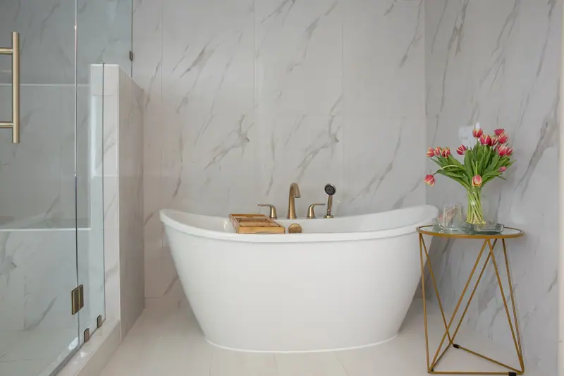Freestanding tub with deck-mounted brushed gold filler and handshower in the reclaimed tub alcove