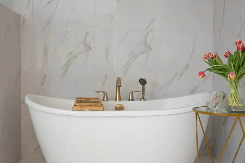 Deck-mounted brushed gold tub filler and handshower on the freestanding tub
