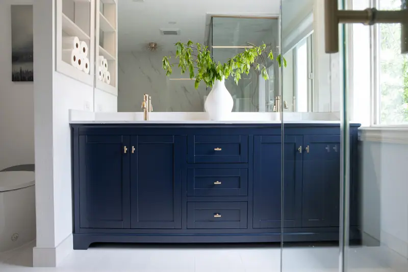 Navy shaker double vanity seen through the frameless glass shower enclosure
