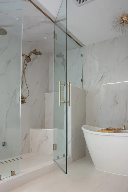 Frameless glass shower door with brushed gold ladder pull