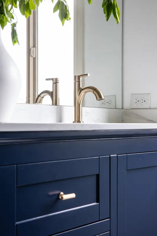 Brushed gold single-hole faucet and quartz counter on the navy vanity