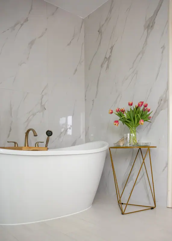 Full-height marble-look porcelain behind the freestanding tub