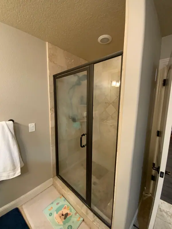 Before the remodel: the original bronze-framed shower with dated tile and a diamond accent band