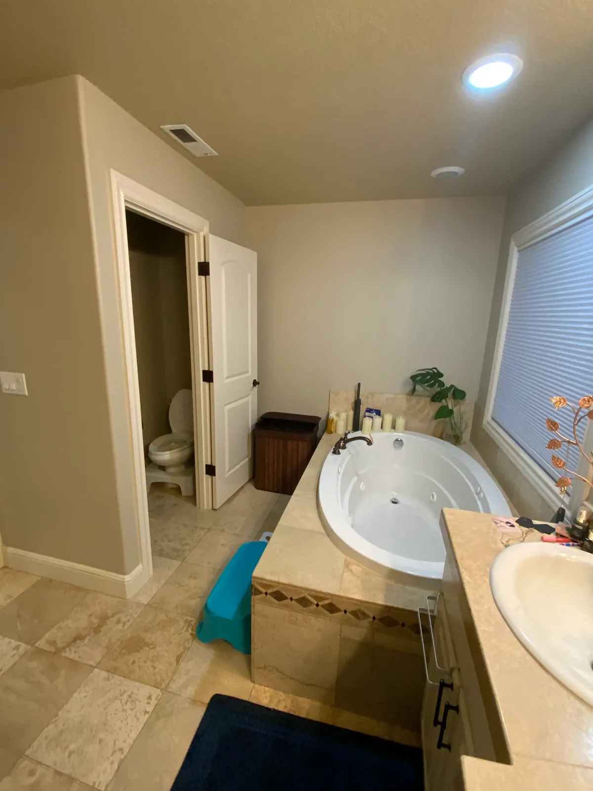 The original Hazel Dell primary bathroom before remodeling, with an oval jetted tub on a wide travertine-look tile deck under the window