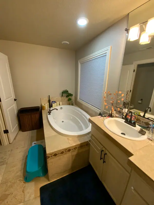 Before the remodel: the jetted tub deck and the cream vanity facing each other across the original bathroom