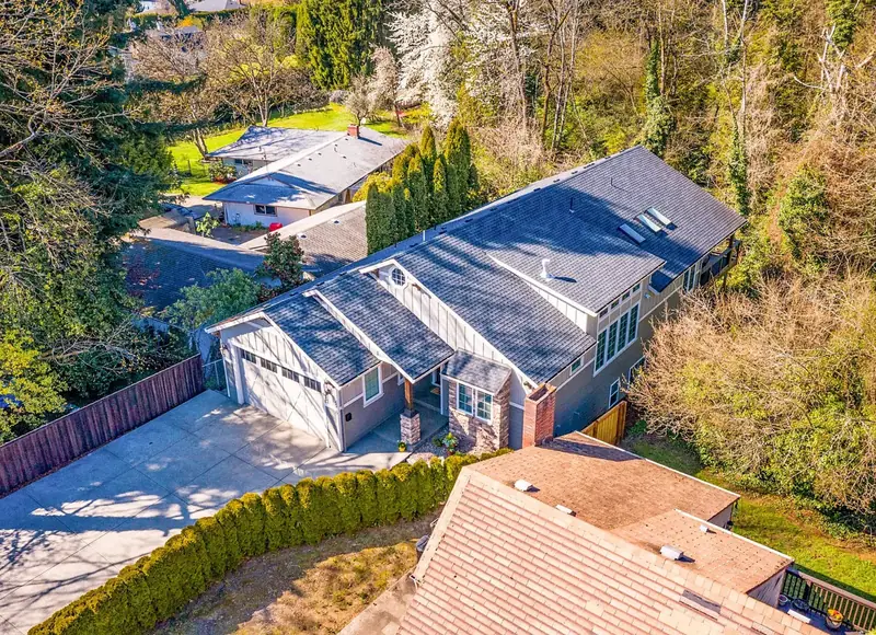 Aerial view of the finished home on its wooded slope, showing the roofline, gabled entry and rear daylight wing — Modern Craftsman Home in Vancouver, WA