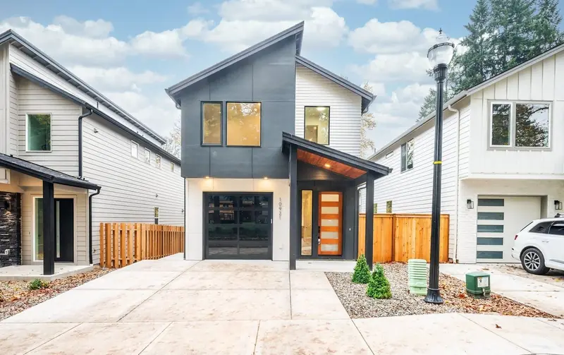 Two-story modern home with a skillion roofline, charcoal and white siding, a glass-paneled garage door and a covered wood-ceiling entry — Modern Two-Story Home with Northwest Style in Vancouver, WA