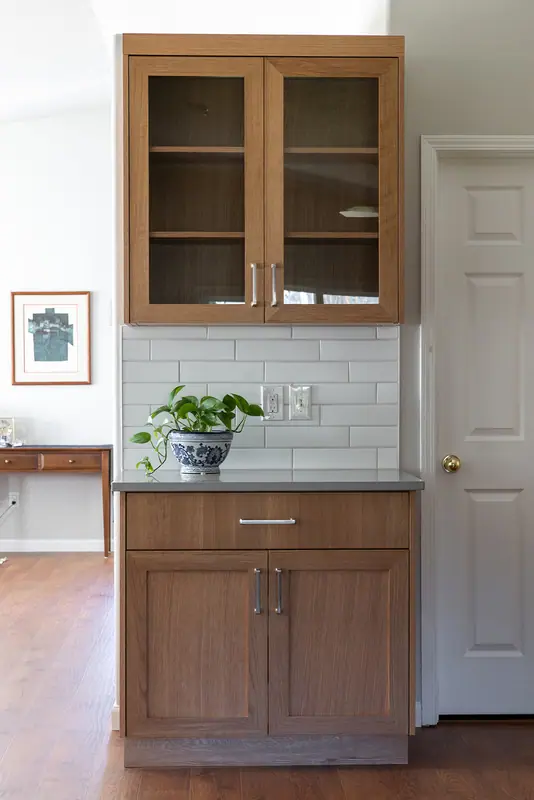 Glass-front white oak hutch cabinet and base cabinet built beside the laundry door