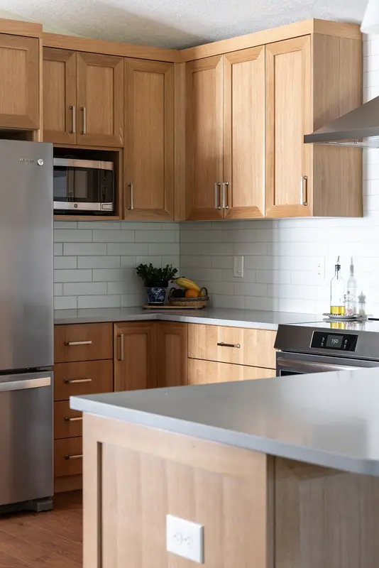 Corner of the kitchen with refrigerator, microwave cabinet, range and wrapping quartz counter
