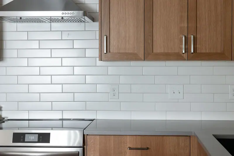 The range wall with hood, white subway tile and Crystal Grey quartz counter run