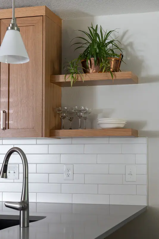 Island sink with pull-down faucet below white oak floating shelves