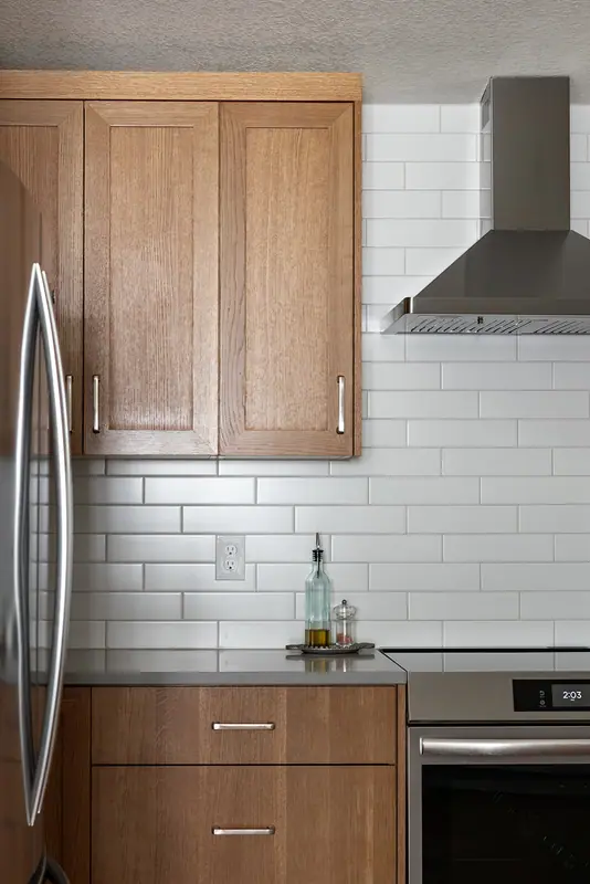 Refrigerator, range hood and subway tile detail in the remodeled kitchen