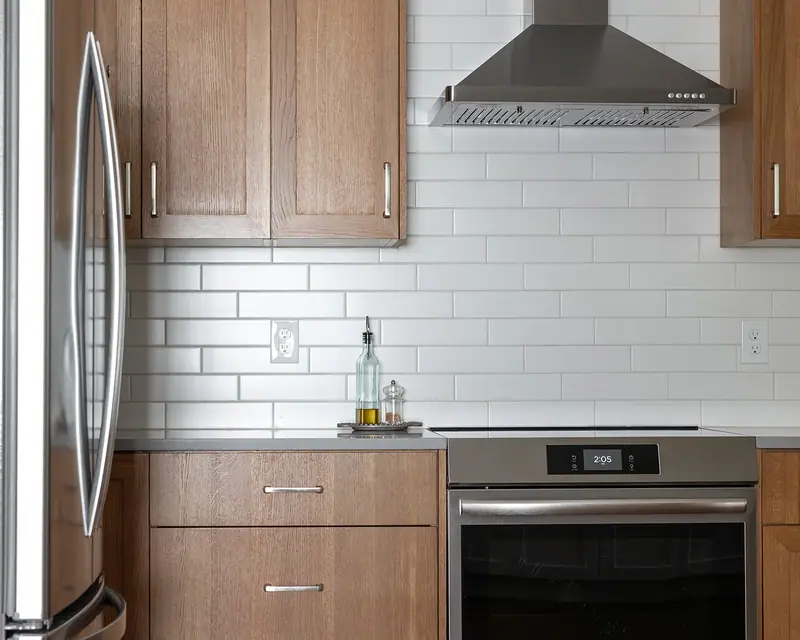 Stainless refrigerator beside the subway tile backsplash and range