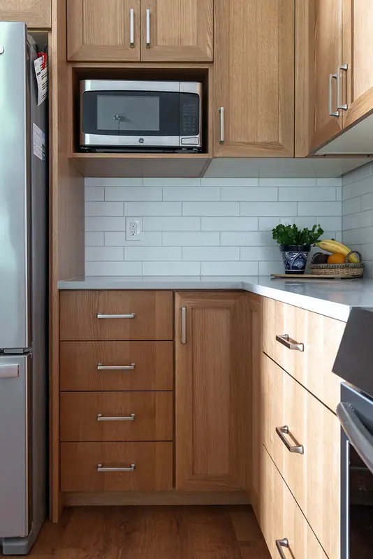 The microwave relocated into its own open cabinet niche above a bank of drawers
